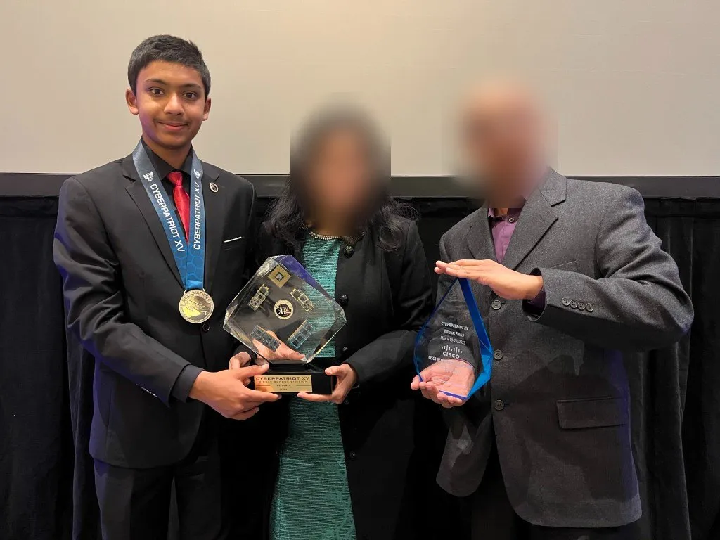 Aditya with his parents holding the CyberPatriot XV trophies