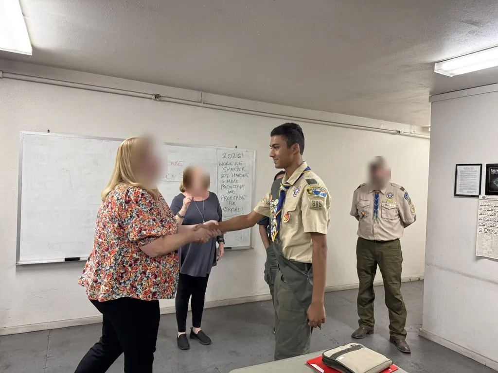 Aditya shaking hands at his Eagle Scout ceremony; other faces blurred