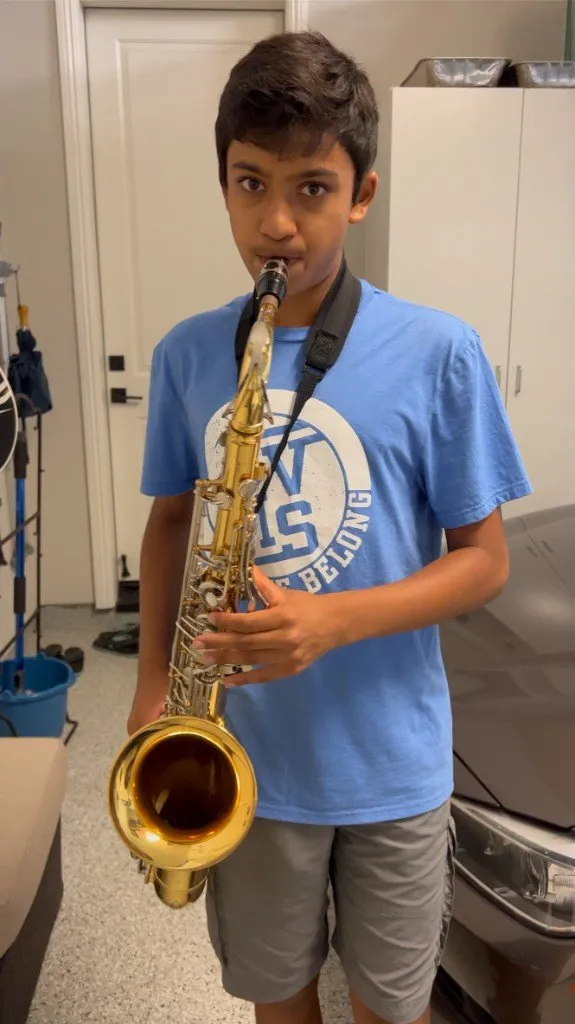 A younger Aditya practicing tenor saxophone in the garage