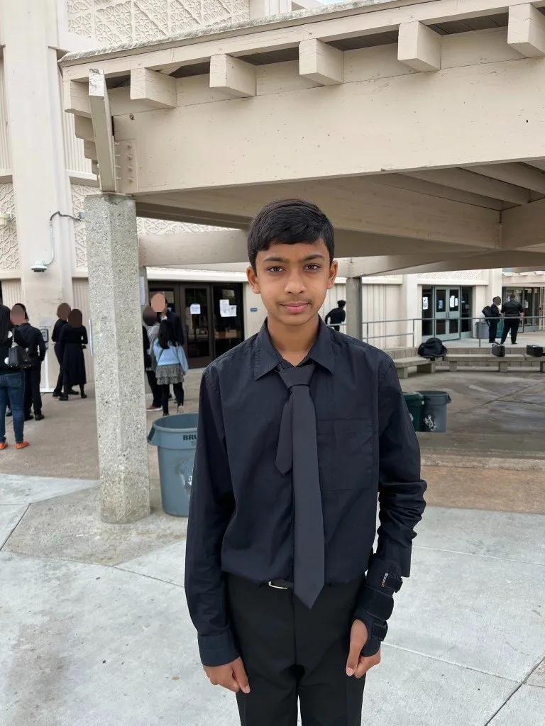 A younger Aditya in concert black outside a performance venue; people in the background blurred
