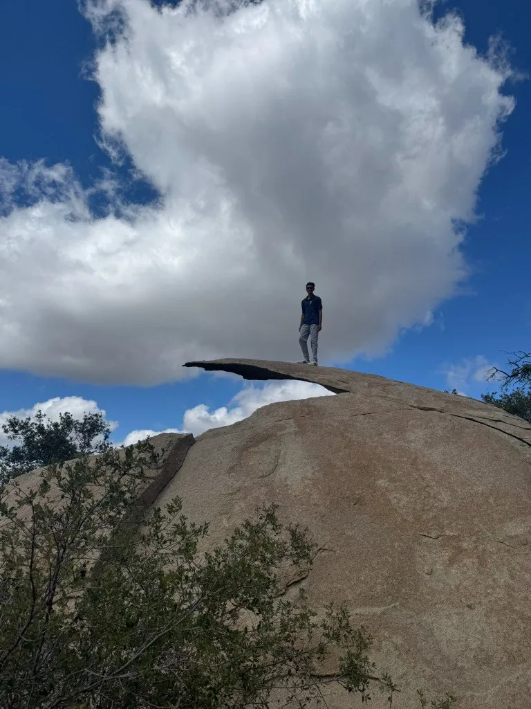 Aditya standing on the edge of Potato Chip Rock under a huge white cloud