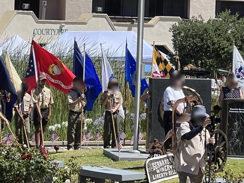 Aditya in his scout uniform at a Fourth of July flag ceremony honoring veterans; other faces are blurred